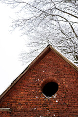 Red Brick Wall With A Circular Window Under A Snowy Tree