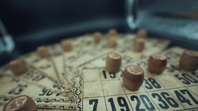 Crane backwards shot of a Bingo desk lottery game, vintage cards with numbers, wooden chips, super slow motion 120 fps, studio lights