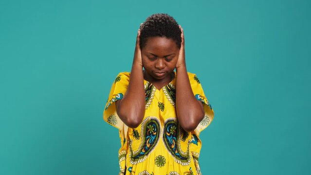 Moral person doing three wise monkeys symbol in studio, covering her eyes, mouth and ears against blue background, See no evil, speak no evil and hear no evil metaphor, wisdom concept. Camera A.
