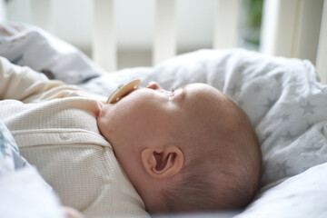                                baby with pacifier in bed before sleep. Pretty six-month old baby...