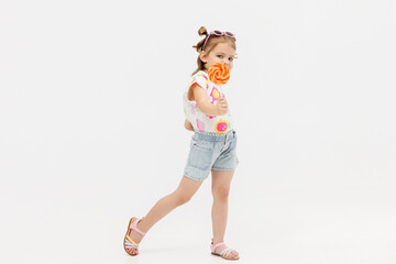 Happy little cute girl with a lollipop on a white background. Happy child enjoying childhood.