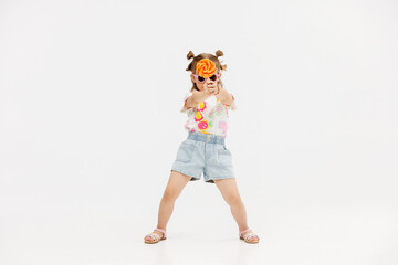 Happy little cute girl with a lollipop on a white background. Happy child enjoying childhood.