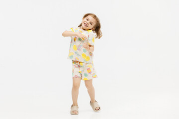 Little girl dancing in the studio on a white background. Happy energetic girl having fun and enjoying her childhood. Concept of fashion, style and happy children's emotions.