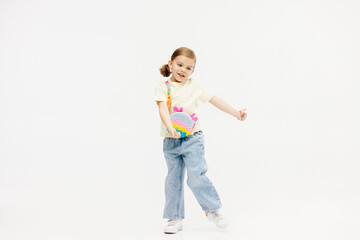 Little girl dancing in the studio on a white background. Happy energetic girl having fun and enjoying her childhood. Concept of fashion, style and happy children's emotions.