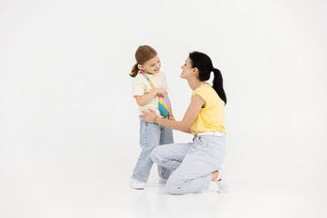 Happy mother and daughter in stylish bright clothes on a white studio background. Concept of fashion, style and parental feelings.