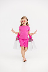 Fashionable, stylish little girl dancing, having fun and posing on a white studio background. Fashion, children's clothing and entertainment concept.
