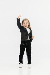 A little business girl dressed in a classic business suit on a light background shows the “Class” gesture. Concept of trust, positivity and business.