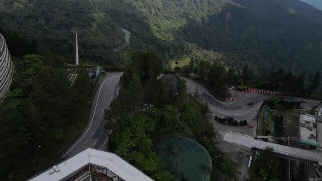 Drone flies over a road in the genting highlands in malaysia - background nature and many mountains with a cable car