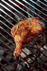 Chicken with rosemary on a grill.