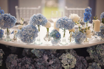 Flowers and candles on table. blue and white flowers decorate the table. Beautiful table set with candles and flowers for a festive event, party or wedding reception. 