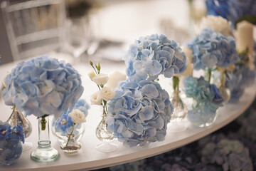 Flowers and candles on table. blue and white flowers decorate the table. Beautiful table set with candles and flowers for a festive event, party or wedding reception. 