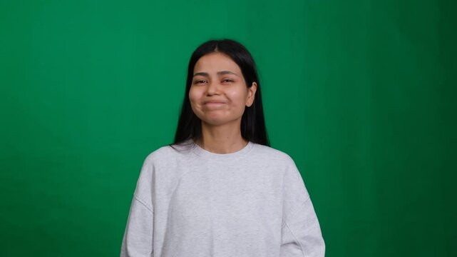 Woman in a studio covers her mouth with her hand, showing a quiet and embarrassed expression. Her gesture conveys secrecy, shock, and worry, capturing an emotional moment of silence and surprise