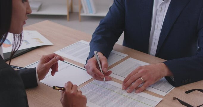 Two business people busy discussing paper financial report in charts diagrams and graphs close up, business partners analysing common sales statistics presenting deal benefits at meeting, mentor study