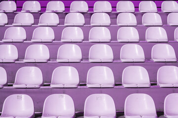 Empty rows of purple stadium seats in an outdoor setting, texture, background.