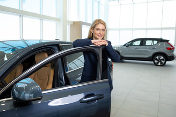 Elegant beautiful woman near the new car in a showroom
