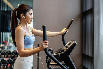 Young asian girl jogging on a treadmill in a gym, Muscular athletes actively training in the gym, Female training at fitness center. Woman exercising cardio workout, exercise lose weight, listen music