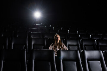 A young woman came alone to the cinema. Black stylish cinema hall. Night film screening