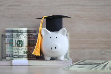 Graduation hat on piggy and banknotes on wooden background, Saving money for education concept