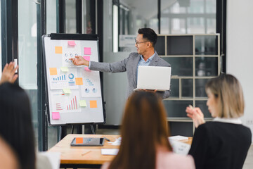 Businessman presenting data and charts to an engaged team during an office meeting, fostering collaboration and discussion.