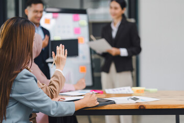Businesswoman presentation with charts and graphs, while team members actively participate by raising hands.