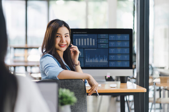 Operator wearing a headset, using a dashboard on laptop for data analysis in modern office.