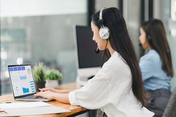 Operator wearing a headset, using a dashboard on laptop for data analysis in modern office. Soft focus