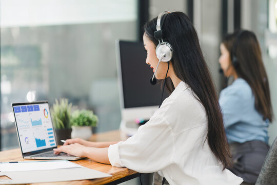 Operator wearing a headset, using a dashboard on laptop for data analysis in modern office. Soft focus