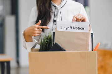Employee packing personal belongings into cardboard box after receiving layoff notice in modern...