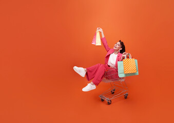 happy Fashionable woman sitting on trolley and shopping bags  with shopping promotion summer sale...