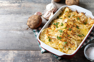 Potato gratin baked with cream and cheese on wooden table. Copy space