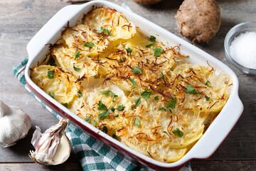 Potato gratin baked with cream and cheese on wooden table. Close up.