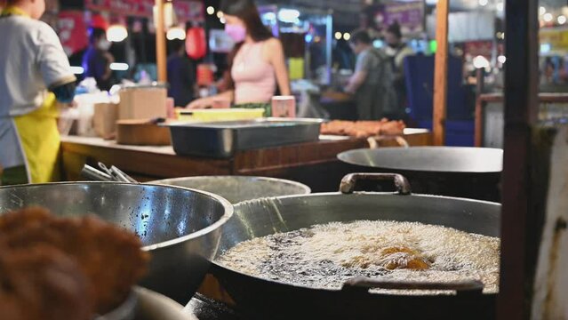 Thai street food. Boiling water in big pan for cooking seafood. People at evening street market