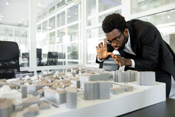 Dark-skinned architect in his office feeling busy and creative while working on the project