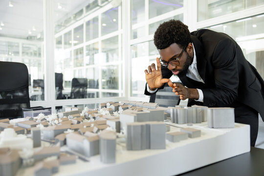 Dark-skinned architect in his office feeling busy and creative while working on the project - Powered by Adobe