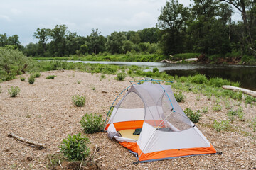 Experience a picturesque camping trip by a riverside with a tent on a pebbly beach. Immerse in...