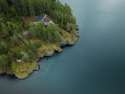 Aerial view of tranquil forest, lake, and house by the coastline, Sooke, British Columbia, Canada.