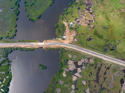 Aerial view of road, lake, bridge, village, and wetlands in Djegbadji, Republic of Benin.