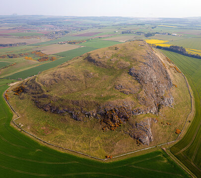 Aerial view of Traprain Law with rocky hill and green meadow, Haddington, Scotland.