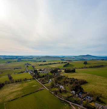 Aerial view of peaceful village nestled among rolling hills and meadows, Chesters, Hawick, Scotland.