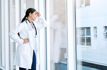Woman, doctor and headache for loss, burnout or mistake with glass window in hospital building....