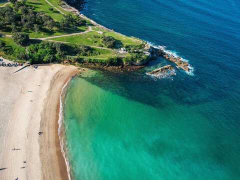 Aerial view of scenic Coogee Beach with rocky shore and green water, Sydney, New South Wales, Australia.