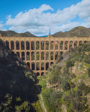 Aerial view of El Acueducto del Aguila bridge with mountains and valley, Nerja, Spain.