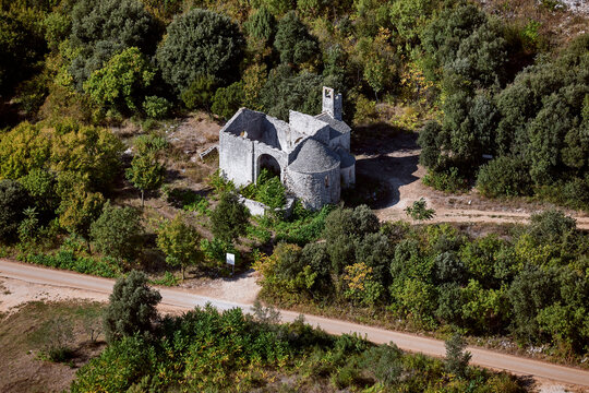 Aerial view of Romanic church ruin surrounded by forest and road, Rovinj, Istria, Croatia.