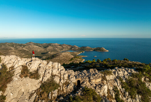 Aerial view of rugged cliff, hiker, and island landscape, Lastovo, Croatia.