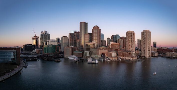 Aerial view of urban skyline at sunset with waterfront and harbor, Boston, Massachusetts, United States.