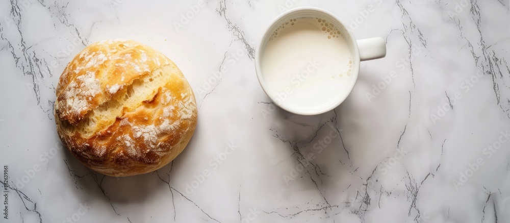 Poster top view image showcasing a white round bread placed alongside a mug of milk on a marble surface, wi