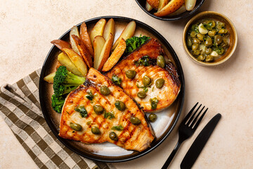 Grilled swordfish with garlic, lemon and capers butter sauce, with baked potatoes and broccoli. Top view.
