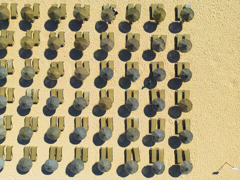 Aerial view of organized beach setup with rows of sunloungers and beach umbrellas, Vilamoura, Faro, Portugal.