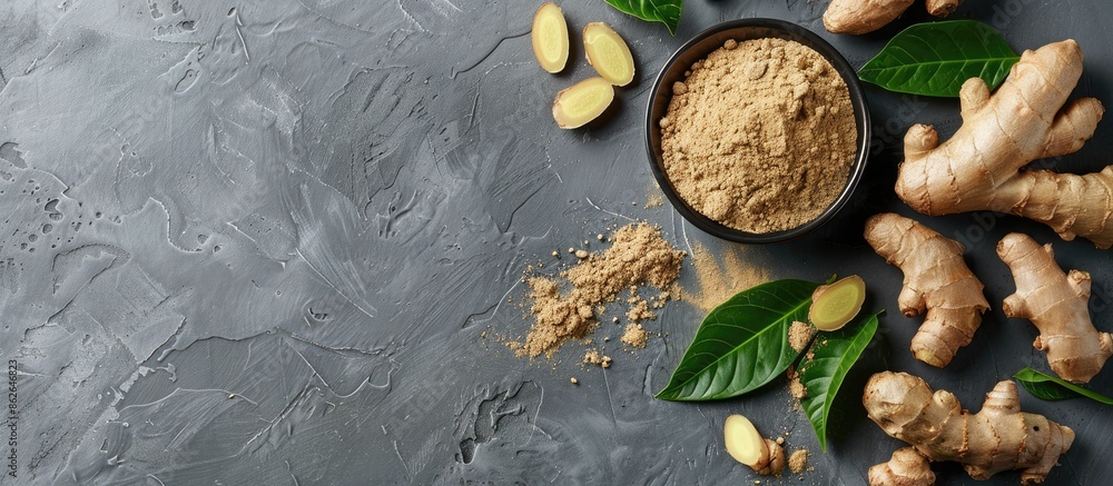 Fototapete ginger powder, fresh root, and leaves displayed on a grey table in a flat lay composition, providing