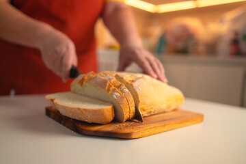 Whole grain bread put on kitchen wood plate with a chef holding gold knife for cut. Fresh bread on table close-up. Fresh bread on the kitchen table The healthy eating and traditional bakery concept